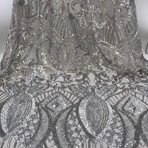 May include: Silver and gold sequined fabric with a geometric pattern. The fabric is sheer and has a delicate, shimmering look.