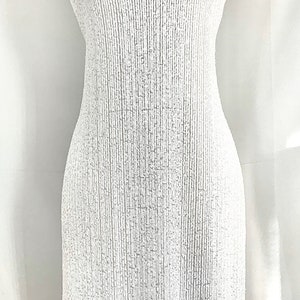 May include: White off-the-shoulder fabric with a textured, ribbed pattern. The fabric is draped over a white dress form.