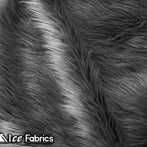 May include: Close-up of a textured, faux fur fabric in shades of gray and white. The long, soft fibers create a wavy pattern. The Ice Fabrics logo is visible in the bottom left corner.