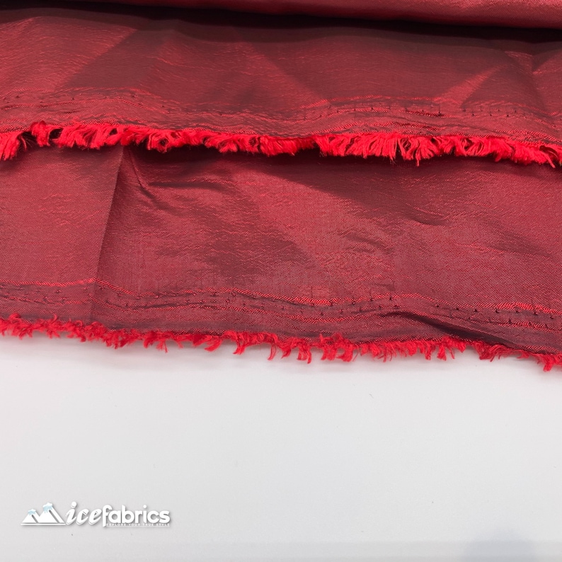 May include: Close-up of a deep red fabric with a slightly textured surface. The fabric has a raw edge with a frayed finish.