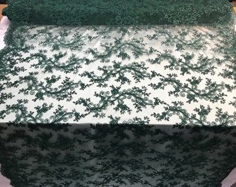 May include: Emerald green lace fabric with a delicate floral pattern. The lace is embroidered with small beads and has a soft, flowing texture.