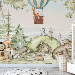 May include: Watercolor illustration of a whimsical forest scene with a hot air balloon, animals, and a cozy hobbit-style home. A swing with stuffed lion and fox toys hangs in the foreground. The scene is filled with trees, animals, and a soft, dreamy color palette.