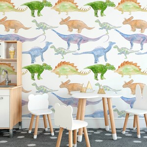 May include: A white play table with four chairs in a room with a wall covered in a watercolor dinosaur wallpaper. The chairs are white with wooden legs and one chair has bunny ears.