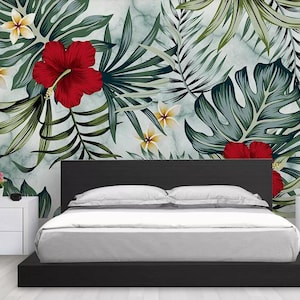 May include: A black platform bed with a white headboard and white bedding. The wall behind the bed features a tropical print with green leaves and red hibiscus flowers.