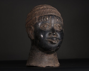 May include: A black ceramic sculpture of a human head with a detailed face and a patterned head covering.