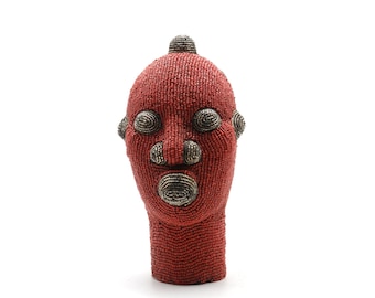 Puede incluir: Una escultura de cabeza humana de cuentas rojas con detalles plateados para los ojos, la nariz y la boca.