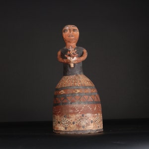 May include: A ceramic figurine of a person wearing a black and brown dress with geometric patterns. The figurine is holding a bouquet of flowers in its hands.