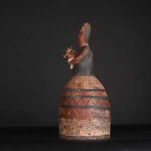 May include: A ceramic figurine of a person with a black and brown painted design. The figurine is standing on a black surface.