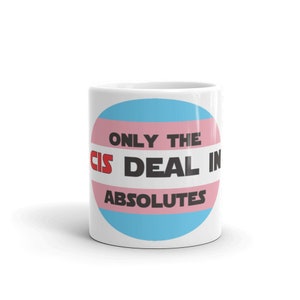 May include: White ceramic mug with a pink, blue, and light blue circle design. The circle has the text "Only the cis deal in absolutes" in black text with the word "cis" in red text.