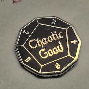 May include: A black and silver metal d20 dice with the words "Chaotic Good" inscribed on the face. The dice has numbers 2, 4, 6, 8, 10, and 12 on the other faces.