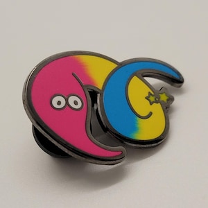 May include: A pink and yellow worm with blue and yellow stripes and two black eyes. The worm is curled up and has a black star on its tail. The worm is a metal pin.
