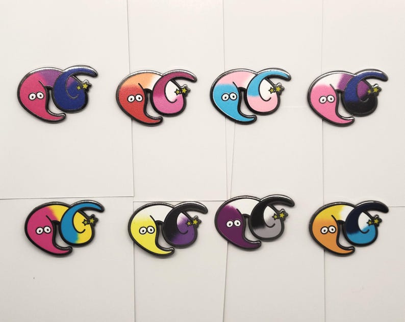May include: Set of ten enamel pins featuring two worm-like figures intertwined. Each pin is a different color combination, including pink and purple, red and pink, blue and pink, pink and black, purple and gray, yellow and purple, pink and blue, orange and blue, and black and gray.