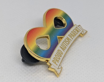 May include: Gold infinity symbol pin with a rainbow design and a white banner that reads "Proud Autism Parent".