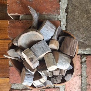 May include: A wooden bowl filled with various pieces of driftwood, including a large antler, a round slice of wood, and several smaller pieces of wood.