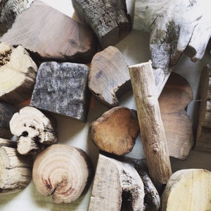 May include: A collection of various sized and shaped pieces of driftwood in shades of brown, gray, and white. The wood has a natural, weathered look.