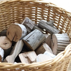 May include: A wicker basket filled with pieces of firewood. The wood is a light brown color and has a rough texture.