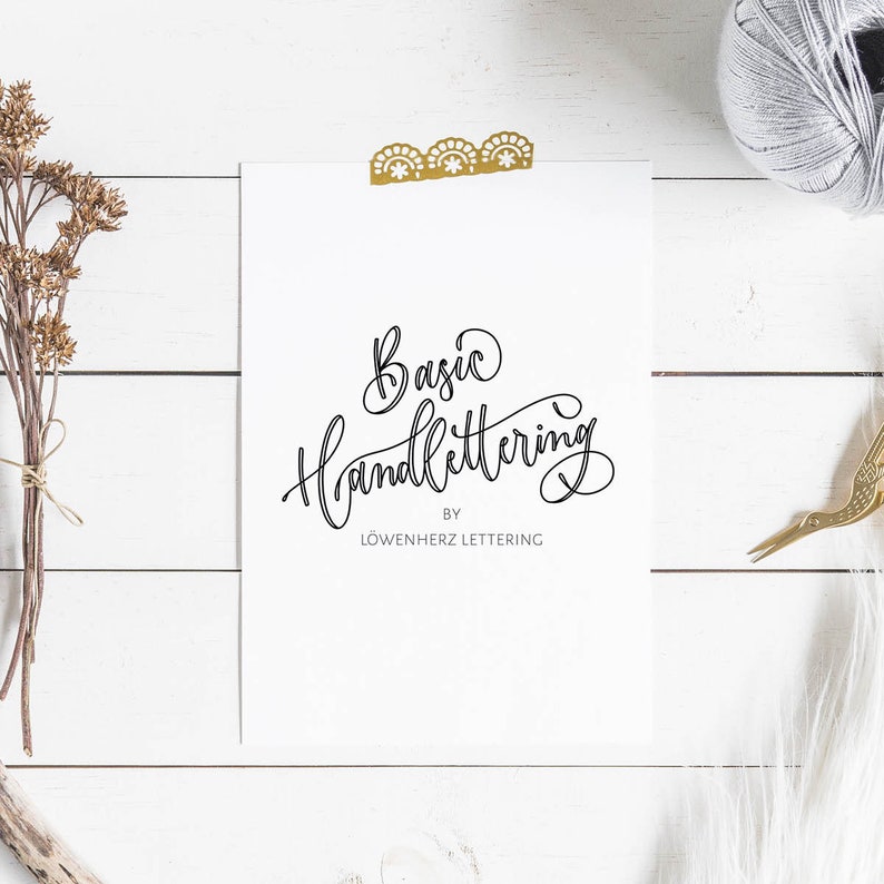 May include: A white card with the text "Basic Handlettering by L&ouml;wenherz Lettering" written in black cursive script.