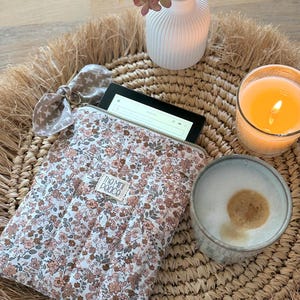 Eine Tablet-Hülle mit floralem Muster und goldenem Reißverschluss. E-Reader Hülle im Musterstoff.