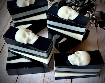 May include: Five bars of black and white soap with a skull design on top. The soap is layered with black, white, and gray stripes.