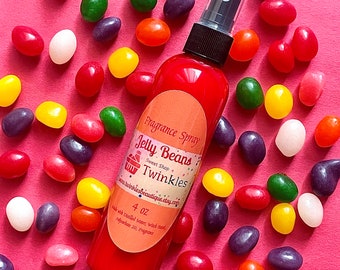 May include: A red glass bottle with a spray nozzle, labeled "Fragrance Spray Jelly Beans Sweet Shop Twinkles" and "4 oz". The bottle is surrounded by colorful jelly beans on a pink background.