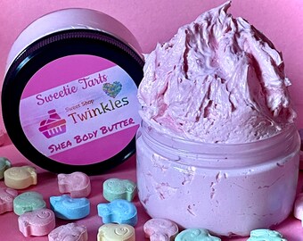 May include: A pink shea body butter in a clear jar with a black lid. The jar is labeled "Sweetie Tarts Sweet Shop Twinkles Shea Body Butter". The jar is surrounded by pastel-colored candy.