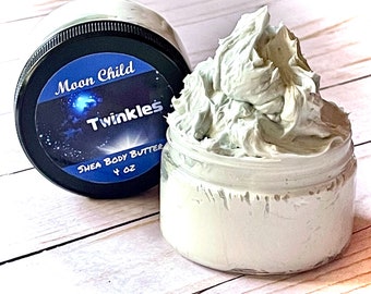 May include: A 4 ounce jar of Moon Child Twinkles Shea Body Butter. The jar is filled with a light green, whipped shea butter. The jar has a black lid with a label that says "Moon Child Twinkles Shea Body Butter 4 oz".