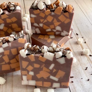 Puede incluir: Barras de jab&oacute;n artesanal con base marr&oacute;n chocolate, incrustadas con piezas de mosaico blancas y marr&oacute;n anaranjado. Cubiertas con malvaviscos blancos, salsa de chocolate y chispas oscuras. Un dulce capricho para el ba&ntilde;o.