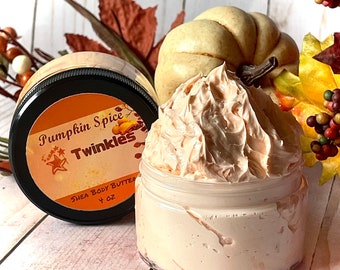 Könnte beinhalten: Zwei transparente Gläser Sheabutter mit Kürbisgewürzduft. Ein Glas ist geöffnet und zeigt eine geschlagene, hellorangefarbene Creme. Das andere Glas hat einen schwarzen Deckel mit einem orangefarbenen Etikett mit der Aufschrift "Pumpkin Spice Twinkles" und "Shea Body Butter 113 g."