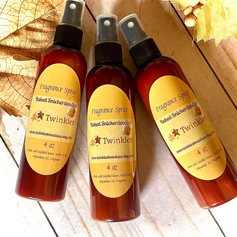 K&ouml;nnte beinhalten: Drei braune Glas-Spr&uuml;hflaschen mit gelben Etiketten. Die Etiketten zeigen "Fragrance Spray", "Baked Snickerdoodles" und "Twinkles". Jede Flasche enth&auml;lt 118 ml Duft.