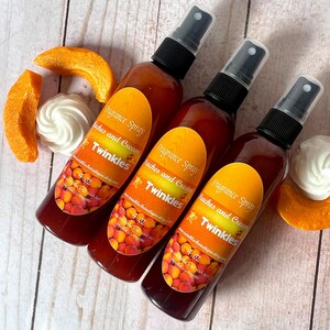 May include: Three brown glass bottles with black spray tops and peach and cream scented fragrance spray. The labels are orange and yellow with the text "Fragrance Spray Peaches and Cream Twinkles" and "4 oz".