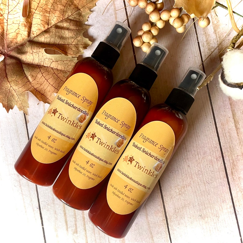 K&ouml;nnte beinhalten: Drei braune Glasflaschen mit schwarzen Spr&uuml;hk&ouml;pfen. Jede Flasche hat ein gelbes Etikett mit dem Text "Fragrance Spray", "Baked Snickerdoodles", "Twinkles" und "4 oz".