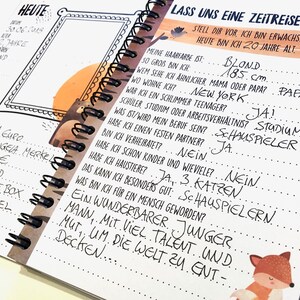 Puede incluir: Un cuaderno con una ilustraci&oacute;n en blanco y negro de un oso en la portada. El cuaderno tiene una encuadernaci&oacute;n en espiral y est&aacute; abierto en una p&aacute;gina con texto escrito a mano en alem&aacute;n. El texto incluye preguntas sobre la vida de una persona, como el color de su cabello, su altura y si tiene hijos. La p&aacute;gina tambi&eacute;n incluye un dibujo de un zorro.