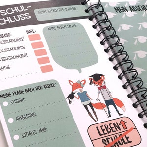 Op de afbeelding: Een groen en wit spiraalnotitieblok met een afstudeerthema. De omslag toont een vos die een afstudeerpet draagt en een diploma vasthoudt. De tekst op de omslag luidt "Mein Schul-Abschluss" en "Mein Abschlussfoto!"