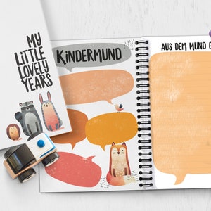 Puede incluir: Un cuaderno blanco de espiral con una ilustraci&oacute;n colorida de animales y burbujas de di&aacute;logo. La portada dice "My Little Lovely Years" y "Kindermund" con el texto "Aus dem Mund Gepurzel" en el lado derecho.
