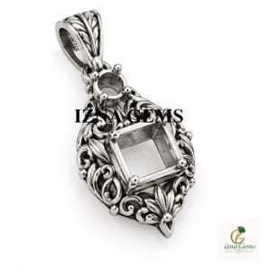 Puede incluir: Un colgante de metal plateado con un intrincado diseño de volutas, un engaste cuadrado central y un engaste circular más pequeño encima. El texto IZNA GEMS es visible en el centro del colgante de metal.