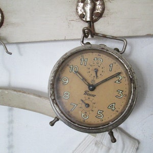 May include: A vintage silver alarm clock with a cream-colored face and black numbers. The clock has a small second hand and the word "Boxer" printed on the face.