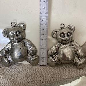 May include: Two silver teddy bear charms, each about 6 cm tall, with a textured surface and a loop for hanging.