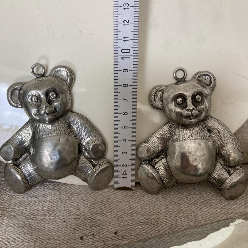 May include: Two silver teddy bear charms, each about 6 cm tall, with a textured surface and a loop for hanging.