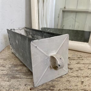 Könnte beinhalten: Ein weißer und grauer Metalltopf mit einem Griff. Der Topf ist aus verzinktem Metall und hat eine patinierte Oberfläche.