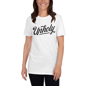 Puede incluir: Camiseta blanca de manga corta con texto negro que dice "Unholy" en una fuente estilizada.