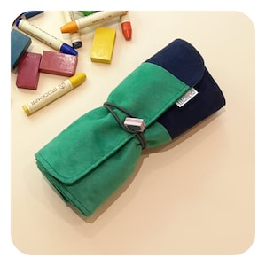May include: A green and blue rolled pencil case with a black elastic band and a brown label that says "molino".