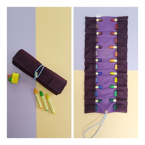 Könnte beinhalten: Eine violette Stoffrolle mit einem blauen Kordelzug. Die Rolle ist mit bunten Buntstiften gefüllt. Die Rolle ist aufgerollt und mit einem blauen Gummiband zusammengebunden. Drei Buntstifte liegen auf einer gelben Oberfläche.