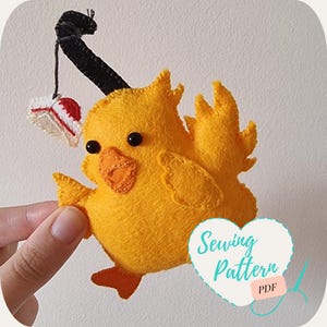 May include: A yellow felt chick with black eyes and a red beak holding a book in its beak. The chick is attached to a black string. The image has the text "Sewing Pattern PDF" on it.