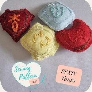 May include: Four felt squares with embroidered symbols, representing the four tank jobs in the video game Final Fantasy XIV. The squares are in red, yellow, blue, and orange. The text "FFXIV Tanks" is on a pink rectangle. The text "Sewing Pattern PDF" is on a teal heart.