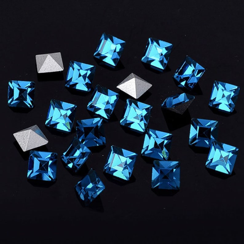 May include: Assortment of blue square rhinestones with a silver pyramid-shaped setting.