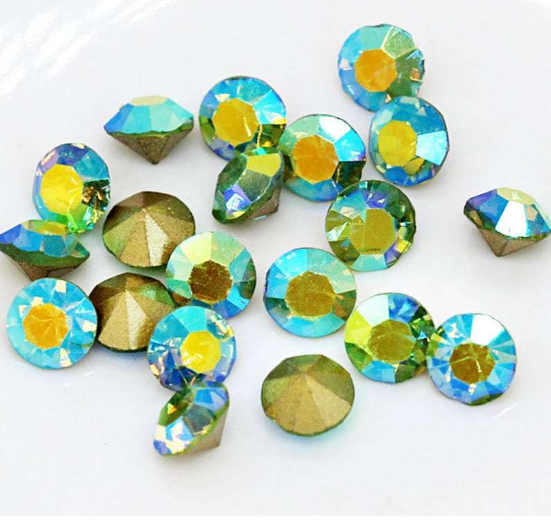Pu&ograve; includere: Assortimento di strass verdi e blu iridescenti. Gli strass hanno un design sfaccettato e un retro piatto.