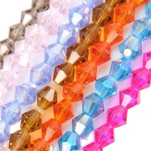 May include: Assortment of faceted glass beads in various colours, including pink, blue, brown, orange, and clear. The beads are arranged in rows, creating a colourful and eye-catching display.