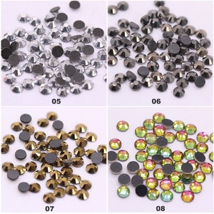 May include: Assortment of rhinestones in various colors, including silver, black, gold, and iridescent green. The rhinestones are arranged in four groups, each with a number below it: 05, 06, 07, and 08.