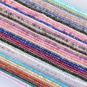 Peut inclure: Un assortiment de perles de pierres précieuses colorées dans diverses nuances, notamment rose, bleu, vert et or. Les perles sont enfilées, créant une présentation vibrante de fournitures de fabrication de bijoux. Les perles sont petites et facettées, reflétant la lumière.