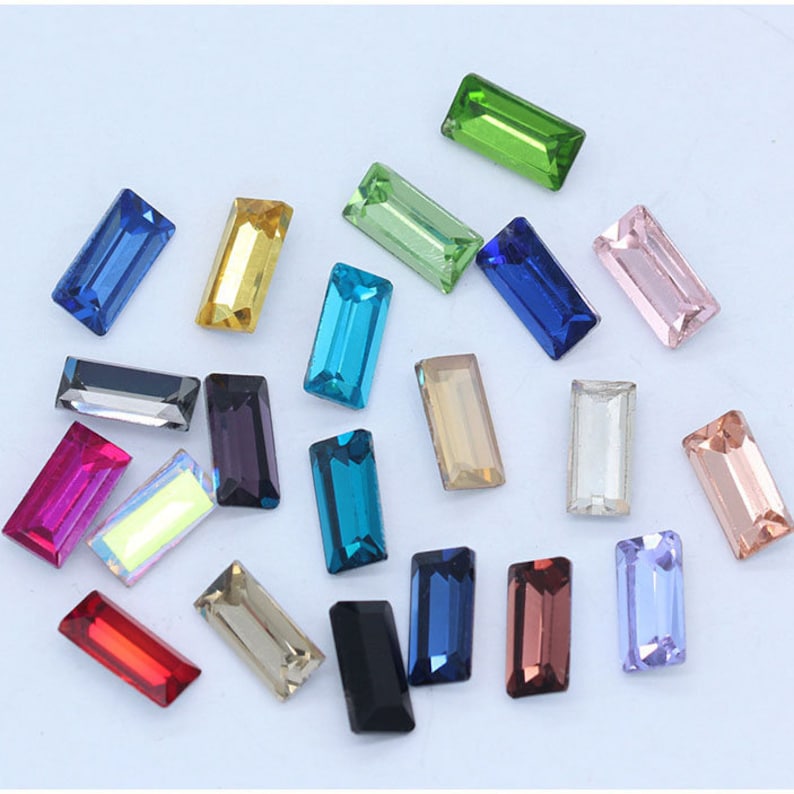 May include: Assortment of colorful rectangular glass rhinestones in various colors, including blue, green, pink, red, and purple.